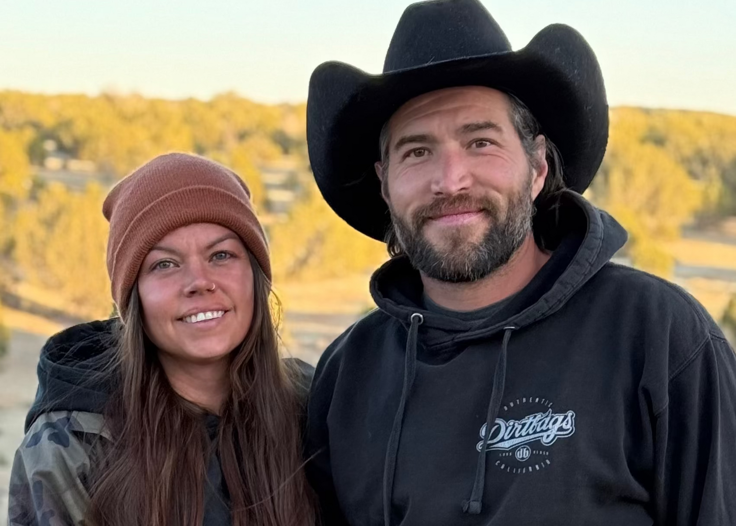 Couple with two dogs standing in a desert landscape